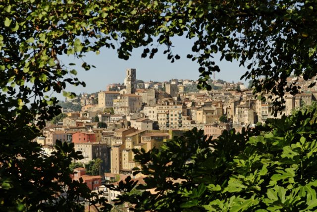 IMAGE: View showing the old town area of Grasse framed by leafy trees