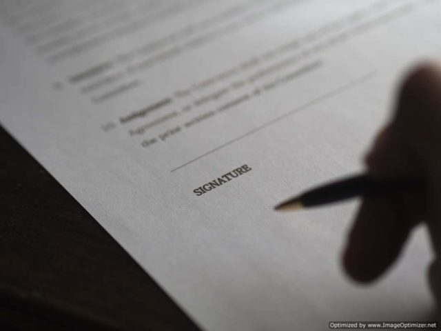 Picture of person signing a document IMAGE: Picture of person signing a document